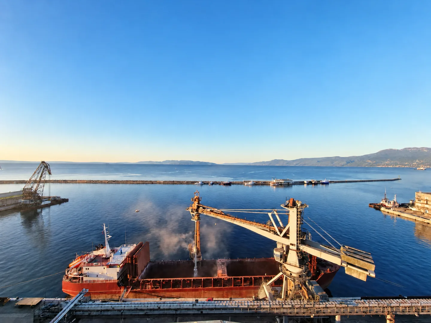 Dry bulk vessel unloading cargo at a coastal terminal