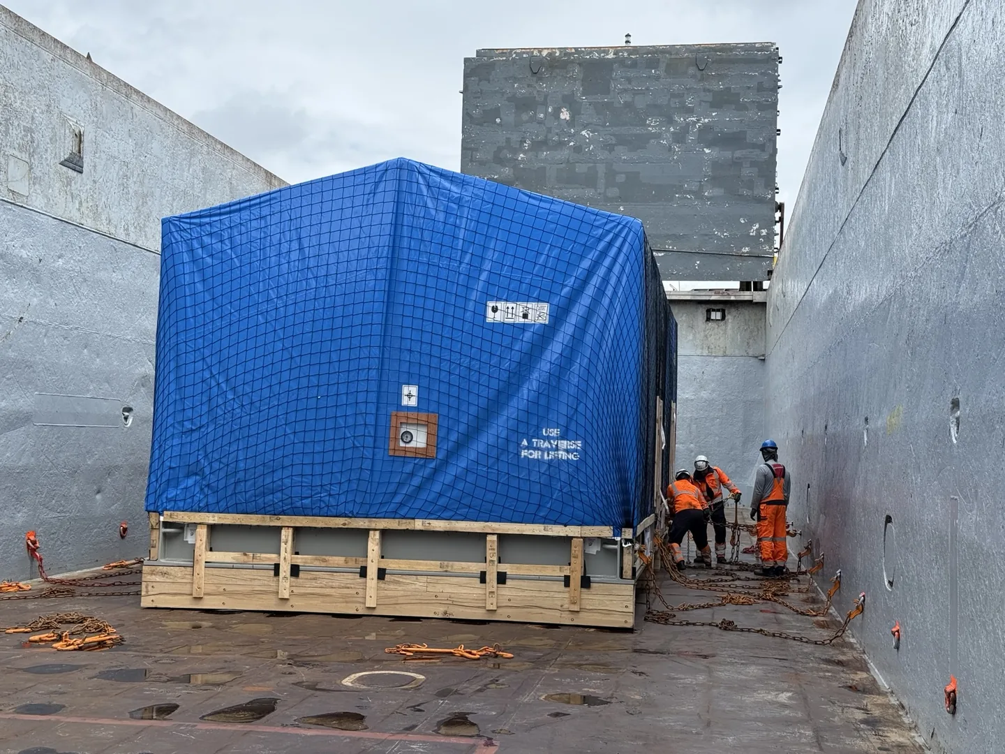 Covered industrial cargo secured with chains inside a vessel hold